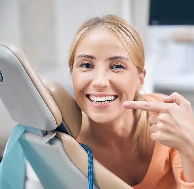 a girl seating on dentist chair and smiling after receiving cosmetic dental treatment in Houston 